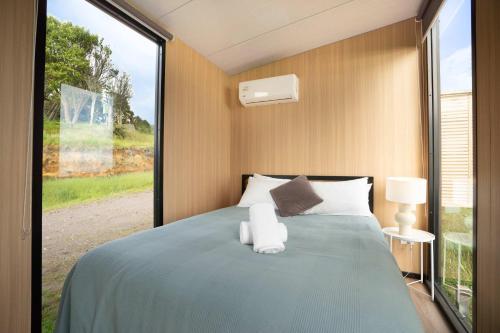 a bedroom with a bed with a large window at Black Horse Cabin 4 by Tiny Away in Waitoki