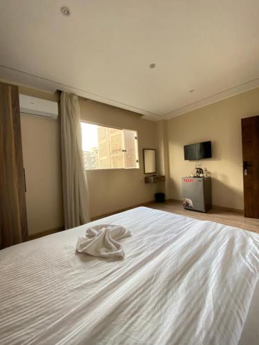 a white bed in a bedroom with a window at Good Nights Pyramids Hotel in Cairo