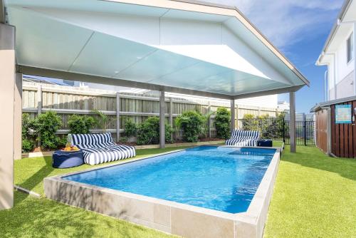 a swimming pool with two chairs and a large umbrella at Surf and Dunes in Yamba