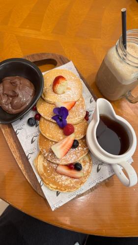 a plate of pancakes with fruit and a cup of coffee at Elysium Tower Premium Serviced Apartments Facing Centaurus Mall Islamabad in Islamabad
