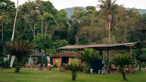 a small house in a field with palm trees at Drop House Hostel in Ubatuba