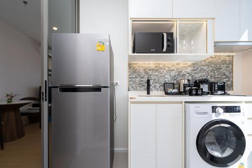 a kitchen with a refrigerator and a washing machine at Oakwood Suites Tiwanon Bangkok in Nonthaburi