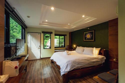 Namtok Sarika Resotel في ناخون نايوك: غرفة نوم بها سرير كبير وتلفزيون