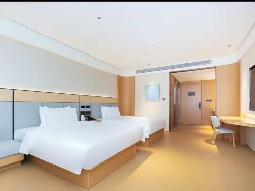 een grote hotelkamer met een groot bed en een bureau bij JI Hotel Suzhou Dushu Lake Ecological Park in Suzhou