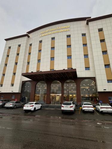 الجوهرة بارك 4 للشقق المخدومة في حفر الباطن: مبنى كبير به سيارات متوقفة في موقف السيارات