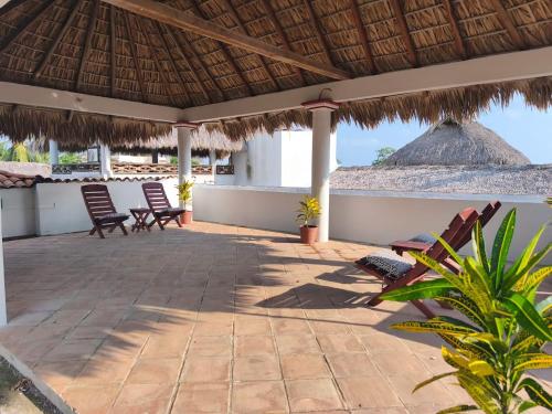 um pátio com cadeiras e um telhado de palha em Casa ola Rinconada Piscina Starlink 5 min caminando a bahía Carrizalillo em Puerto Escondido