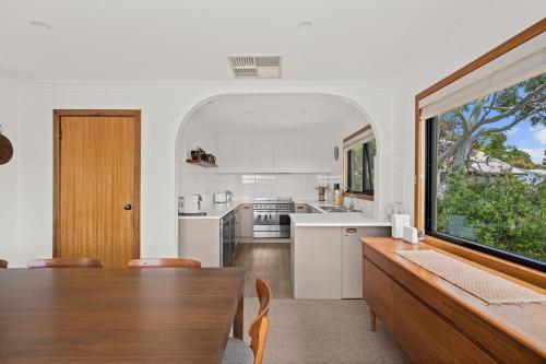 a kitchen with a dining table and a large window at Port of Call - Port Willunga - C21 SouthCoast Holidays in Port Willunga