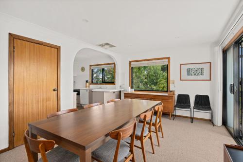 a dining room with a wooden table and chairs at Port of Call - Port Willunga - C21 SouthCoast Holidays in Port Willunga