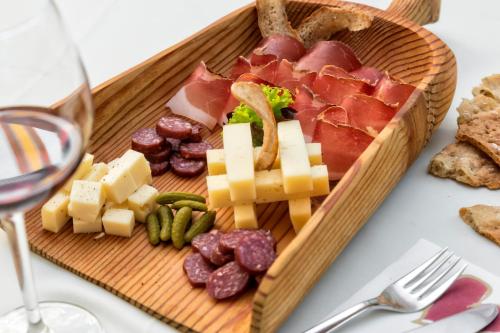 a wooden plate with meats and cheese and a glass of wine at Hotel Gruber in Sesto