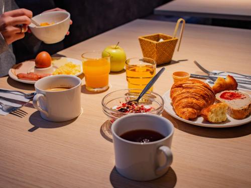- Mesa con desayuno de café, cruasanes y zumo de naranja en ibis Rennes Beaulieu, en Cesson-Sévigné
