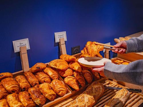 Una persona está alcanzando un plato de pan. en ibis Rennes Beaulieu, en Cesson-Sévigné