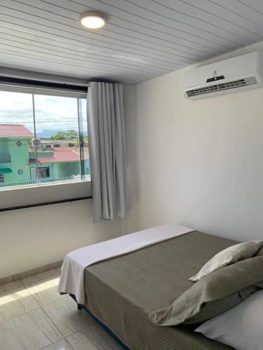 a bedroom with a bed and a large window at Sobradinho Riviera, 3 Quadras do Mar - COM AR CONDICIONADO no quarto in Matinhos