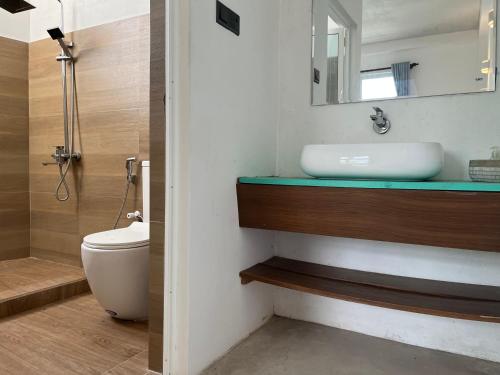 a bathroom with a sink and a toilet and a mirror at Olympus House in Mirissa