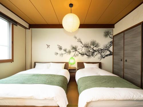 two beds in a small room with a painting on the wall at Bon Stay Matsu201 盆宿 松の間 in Takamatsu