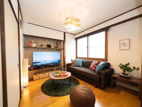 a living room with a couch and a tv at Bon Stay Matsu201 盆宿 松の間 in Takamatsu