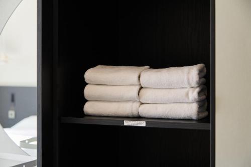 una pila de toallas en un estante en un baño en Cov Stay Haeundae, en Busan