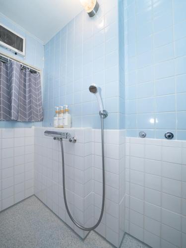 a shower in a bathroom with blue tiles at Bon Stay Matsu201 盆宿 松の間 in Takamatsu