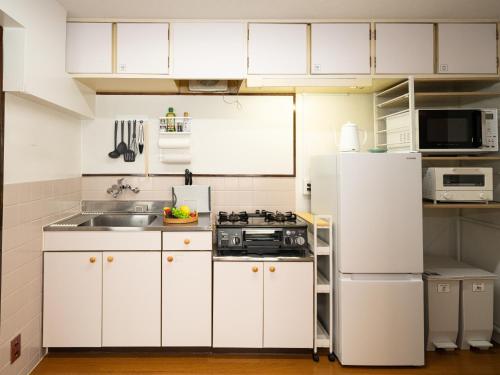 a kitchen with white cabinets and a white refrigerator at Bon Stay Matsu201 盆宿 松の間 in Takamatsu