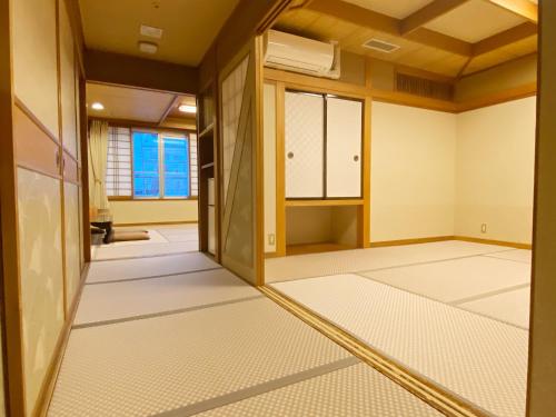 an empty room with white flooring and windows at Ikaho Onsen Todoroki in Shibukawa