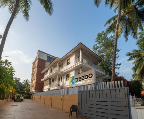 a building on a street with palm trees at Treebo Premium Nova Candolim in Candolim