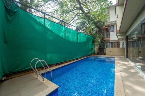 a swimming pool with a green fence next to a building at Treebo Premium Nova Candolim in Candolim