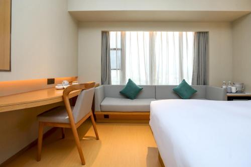 Una habitación de hotel con un sofá, un escritorio y una cama. en JI Hotel Shenzhen Guangming Tianhuicheng, en Bao'an
