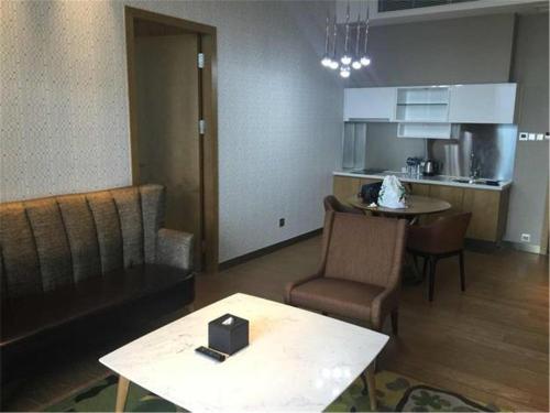 a living room with a table and a kitchen at The Summit Hotel in Zhongshan