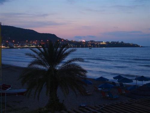 a palm tree sitting on a beach at night at Talgo Suites in Stalida