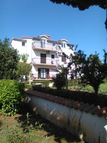 a large white building with a fence in front of it at Apartments Zova in Medulin