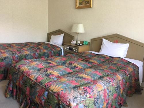 een hotelkamer met 2 bedden en een kleurrijke sprei bij Breezbay Hotel & Resort Gero in Gero