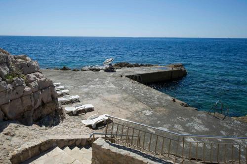 a group of lounge chairs on the side of the ocean at Luxury Apartment Palais Maeterlinck in Nice