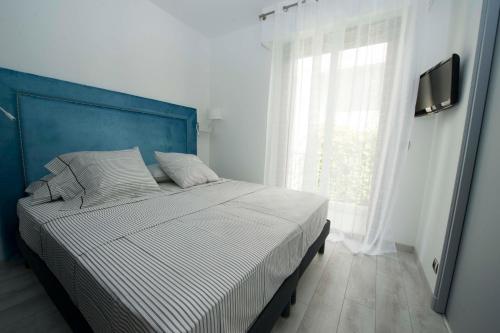 a bedroom with a bed with a blue headboard and a window at Luxury Apartment Palais Maeterlinck in Nice