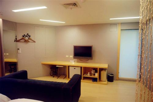a room with a desk with a television on a wall at Every Day Hot Spring Hotel in Jiaoxi