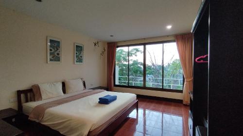 a bedroom with a large bed and a large window at Baan-kawkaew-kata in Ban Karon
