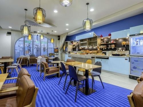 Un restaurante con mesas y sillas y una cocina. en ibis Styles La Rochelle Centre Vieux Port, en La Rochelle