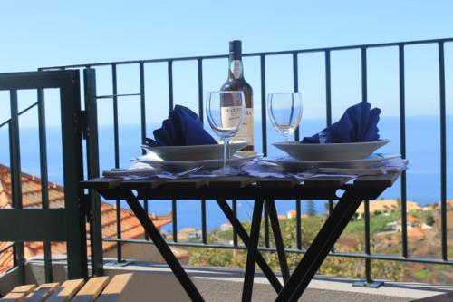 a table with glasses and a bottle of wine on a balcony at Maison Zita in Venda do Atalhinho