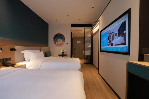 ein Hotelzimmer mit zwei Betten und einem Flachbildfernseher in der Unterkunft Ni Hao in Houshayu