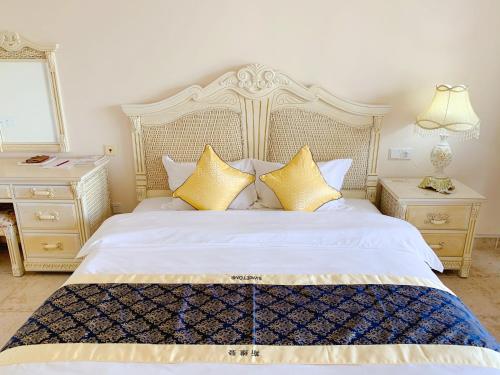 een slaapkamer met een wit bed met gouden kussens bij baya sea view apartment in Xinshi