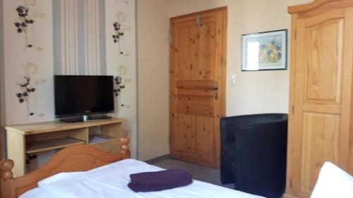 a bedroom with a bed and a television and a door at Landhotel "Lichte Aue" Lichtenau in Stützengrün