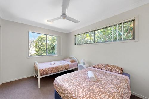 ノース・レイクスにあるMango Hill 3 Bedroom Family Accommodationのベッドが2つと窓が2つある寝室