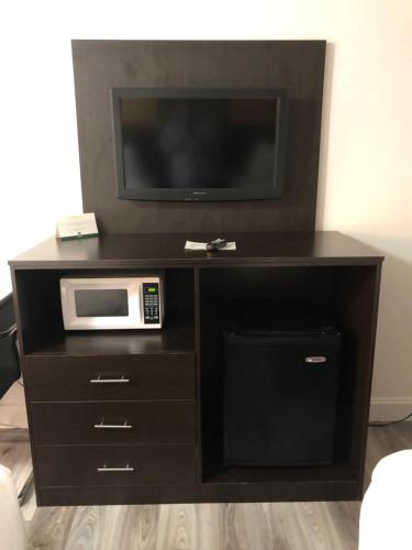 a black entertainment center with a microwave and a tv at Green Palms Extended Stay in Kissimmee