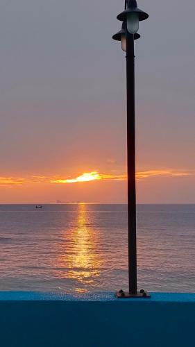 a street light next to the ocean at sunset at Friend Guesthouse , Kho Lanta in Ko Klang