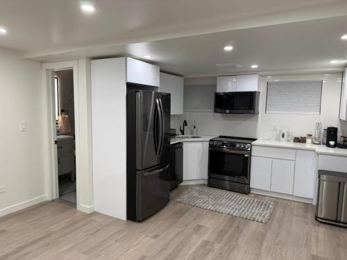 una cucina con elettrodomestici in acciaio inossidabile e armadietti bianchi di Pelham parkway North a Baychester