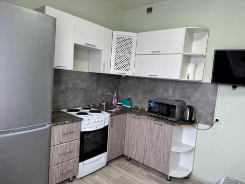 卡拉甘达Республики的厨房配有白色橱柜、炉灶和微波炉。