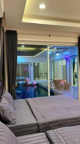 a bedroom with a swimming pool with a bed in the foreground at Cocktail Poolvilla Pattaya in Na Jomtien