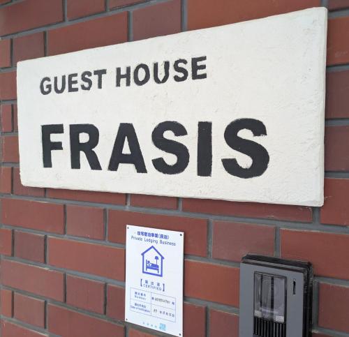 a sign on a brick wall with a guest house frasis at Frasis in Wada