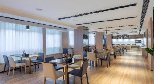 a dining room with tables and chairs in a restaurant at Echarm Hotel Guangzhou North Station Cultural Tourism City in Huadu