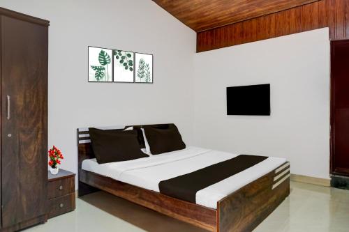 Hotel O Malavli Lonavala في لونافالا: غرفة نوم بها سرير وتلفزيون