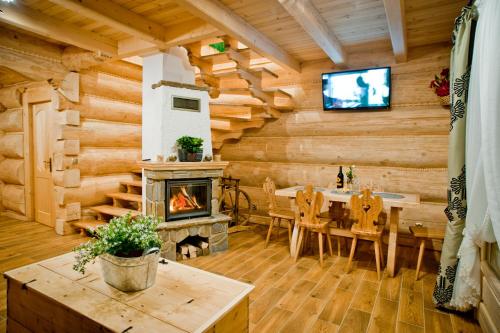 a dining room with a fireplace in a log cabin at Domki Prokop in Ciche
