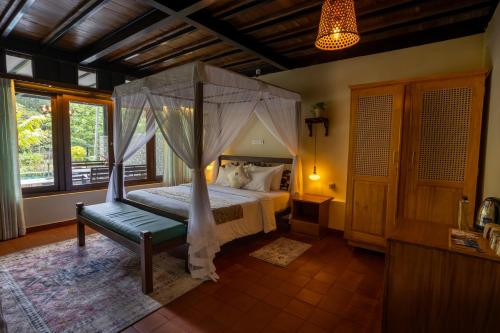 a bedroom with a canopy bed and a chair at Wild Monkey Jungle Villa - 4 Bedroom Villa in Unawatuna